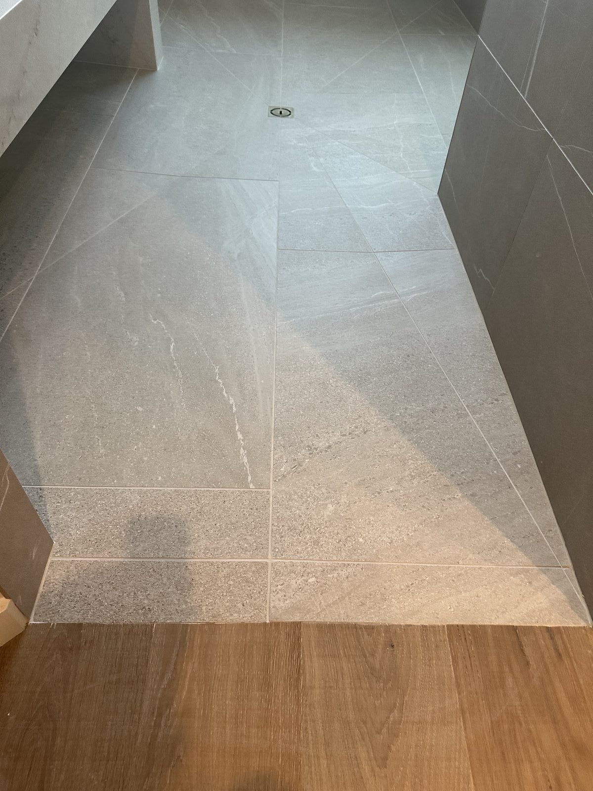 Gray large format tile with wood-look accent strip detail in bathroom shower