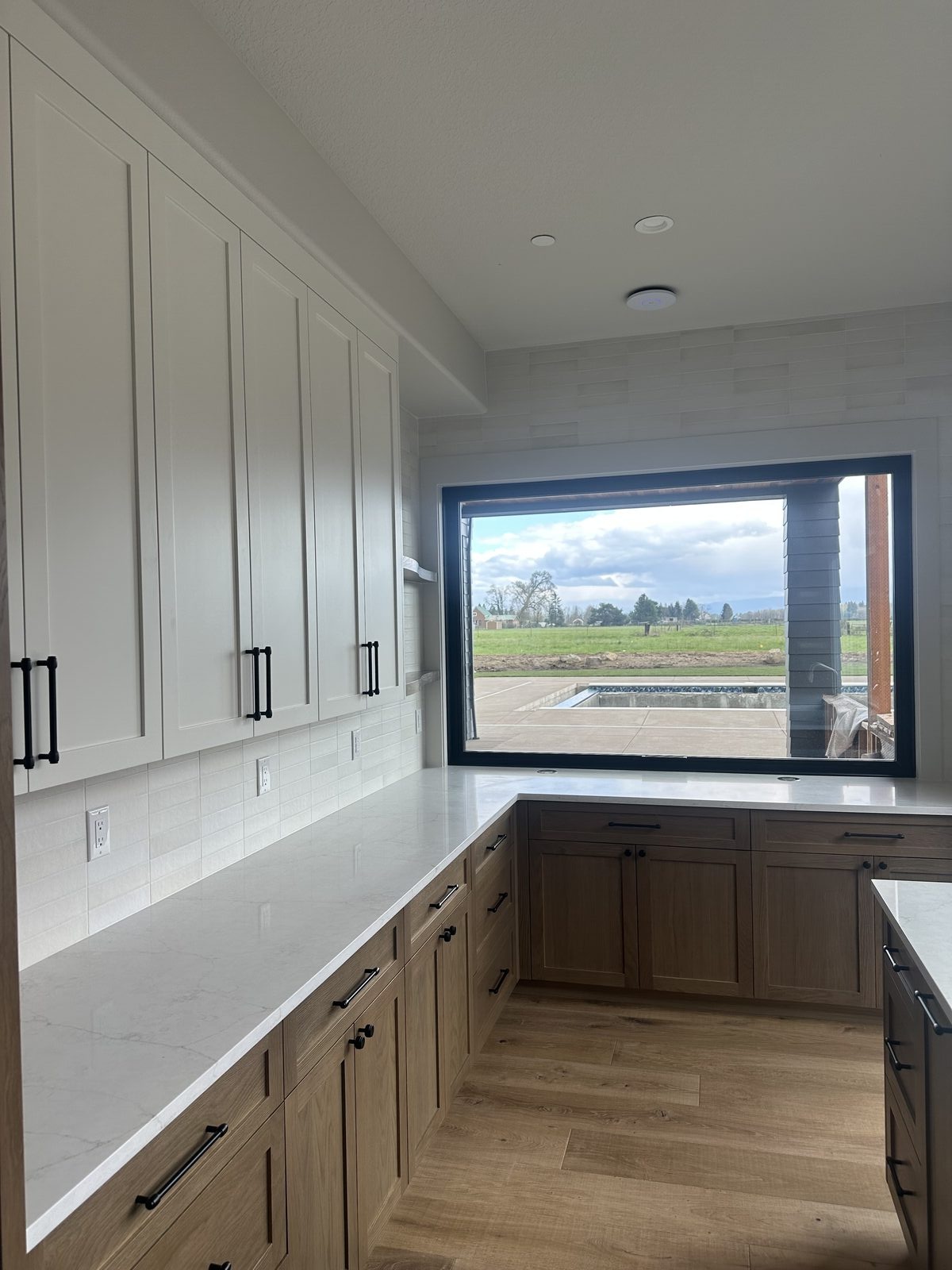Kitchen tile installation with white quartz countertops and modern cabinetry