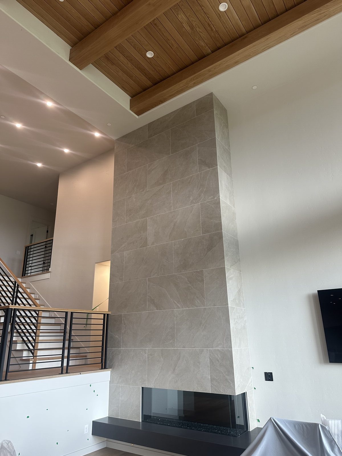 Floor-to-ceiling tile column surrounding a fireplace in a modern living room